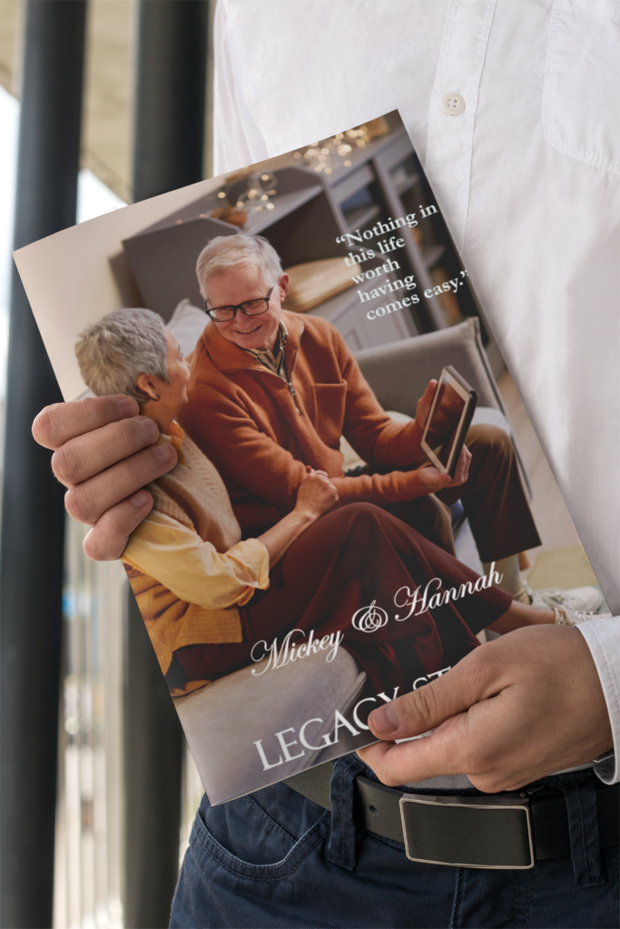 Person holding a custom legacy book titled ‘Mickey & Hannah’ featuring an elderly couple smiling warmly at each other with the quote ‘Nothing in this life worth having comes easy.